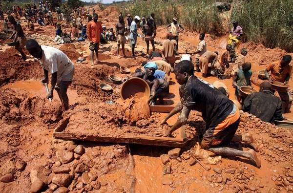 Muddied prospectors pan for gold in Manica Province